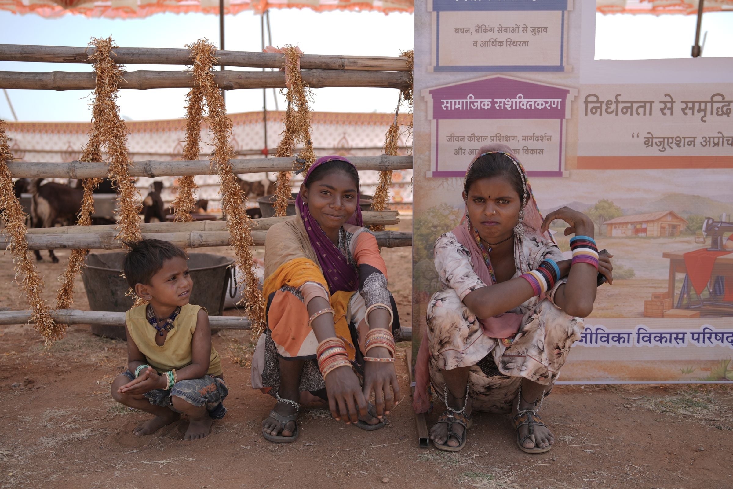 Women and a child beside a social-empowerment display at a rural community event