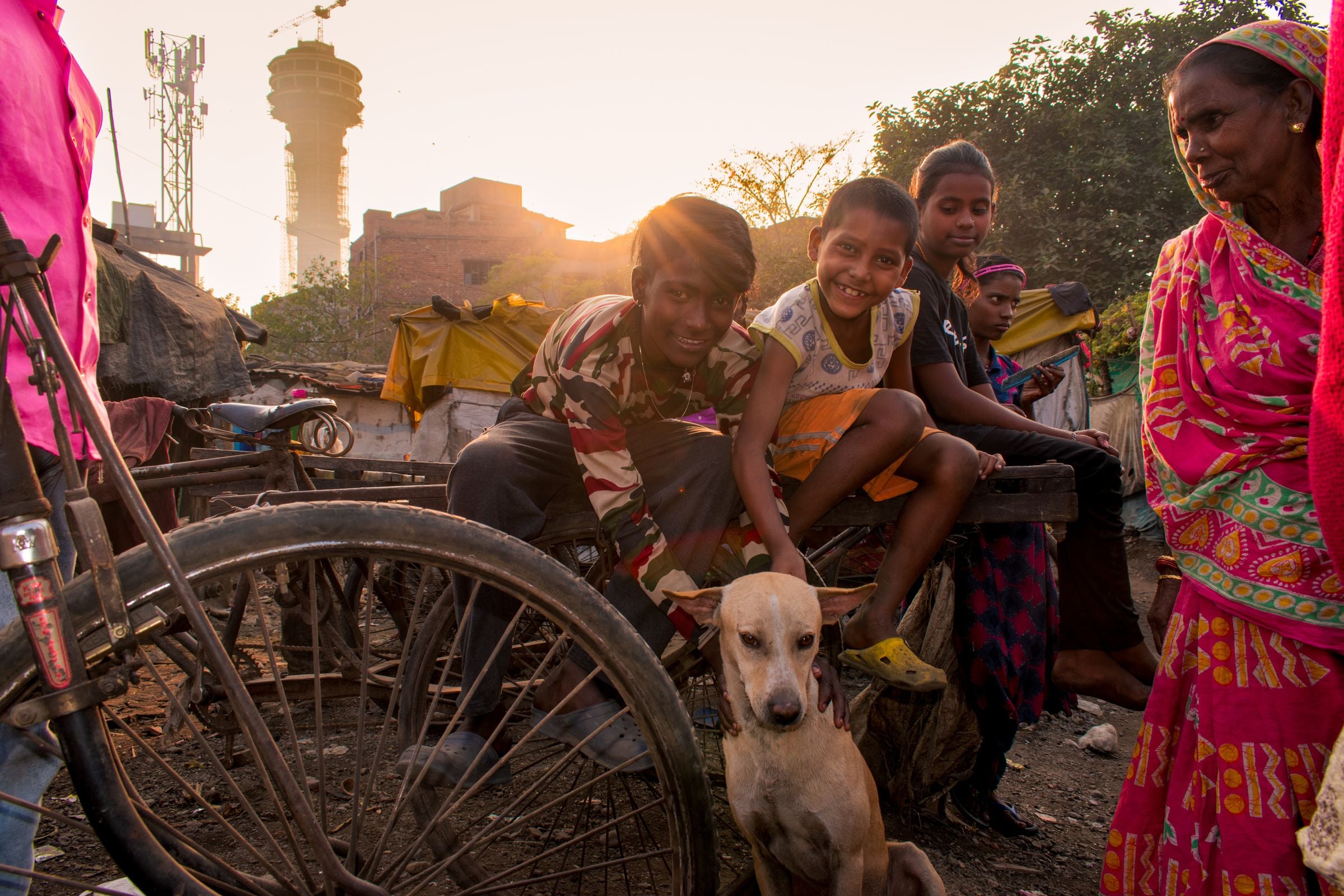 Smiling children and adults gathered with a street dog in an Indian neighbourhood